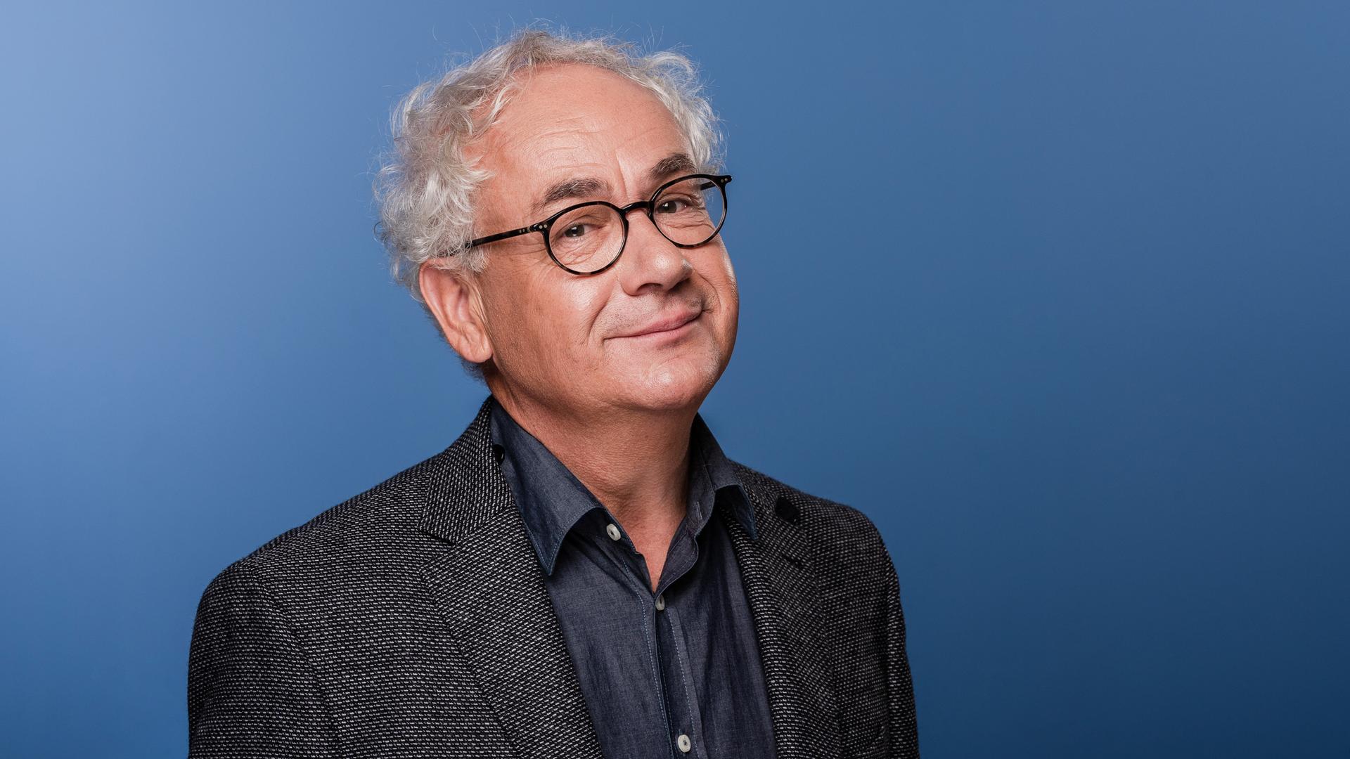 Tom Pauls, ein Mann mit Brille und grauen Haaren im Anzug, blickt verschmitzt in die Kamera. | picture alliance / zb | Kirsten Nijhof