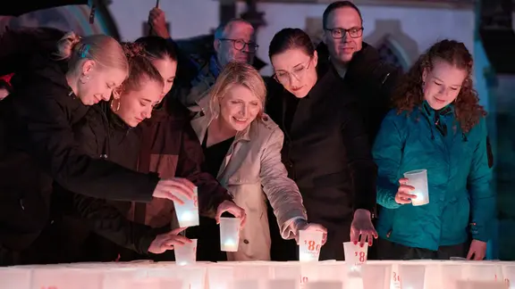 Dirk Panter (2.v.r, SPD), Wirtschaftsminister von Sachsen, Vicki Felthaus (3.v.r.), Bürgermeisterin und Beigeordnete für Jugend, Schule und Demokratie von Leipzig, und Cathryn Clüver Ashbrook (M), Politikwissenschaftlerin, stellen an der Thomaskirche Kerzen in eine leuchtende 89. 