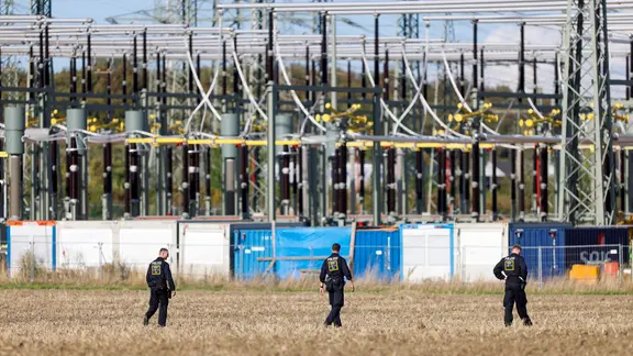Polizisten suchen in der Umgebung des Kraftwerks Weisweiler ein Feld ab.