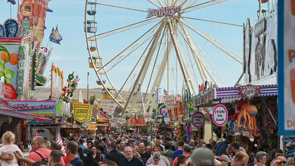 Zahlreiche Menschen auf einem Rummel.