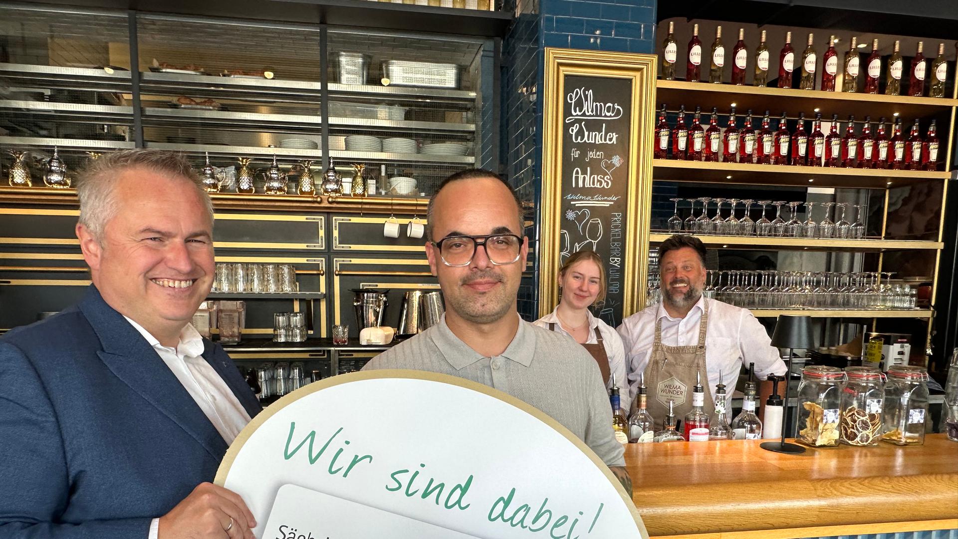 Axel Klein, Hauptgeschäftsführer und Regionalbereichsleiter des DEHOGA Sachsen in der Hauptgeschäftsstelle Dresden und Steve Weichsel, Geschäftsführer des Restaurants Wilma Wunder in Dresden mit dem Team des Restaurants im Hintergrund. | MDR / Katalin Valeš