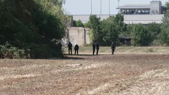 Polizisten auf einem Feld vor Flughafen 