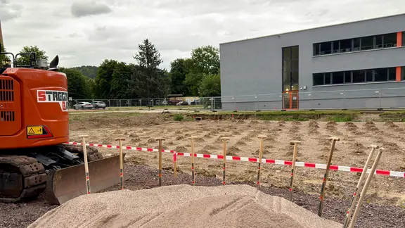 Ein Bagger steht an einem sandigen Baufeld