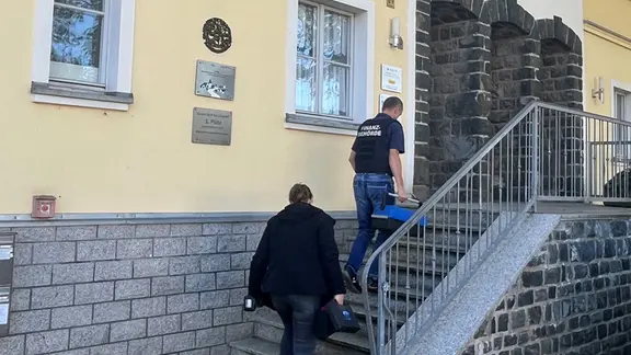 Polizisten laufen die Treppe des Gemeindeamts in Langenwolschendorf hoch.