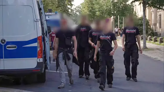 Gruppe mit jungen Erwachsenen mit einheitlicher Kleidung neben Polizeibus