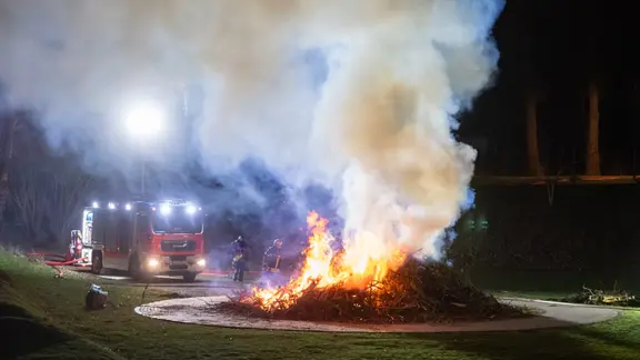 Feuerwehrleute lassen ein Osterfeuer kontrolliert abbrennen. 