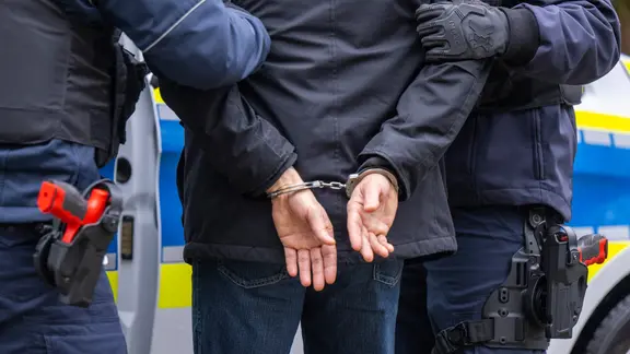 Ein Mann in Handschellen wird von der Polizei festgenommen
