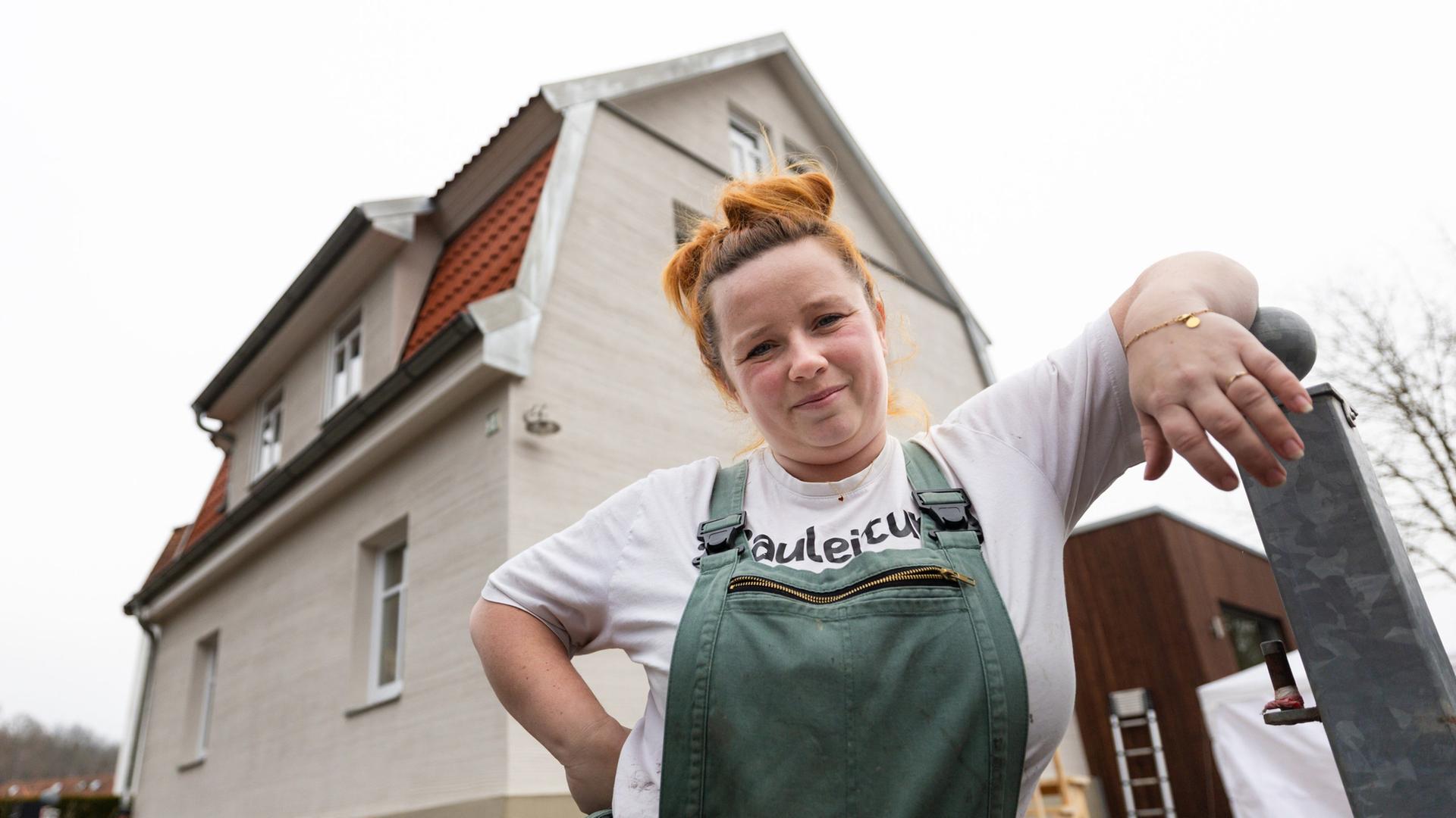Cindy Speich, Bau-Influencerin, steht in Arbeitsmontur vor ihrem Haus und blickt in die Kamera. | picture alliance/dpa | Michael Reichel