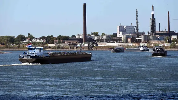 Frachtschiffe fahren auf dem Rhein bei Duisburg-Ruhrort, im Hintergrund ist die industrielle Skyline mit der Chemieindustrie zu sehen. Duisburg-Homberg in Duisburg, 11.08.2026.