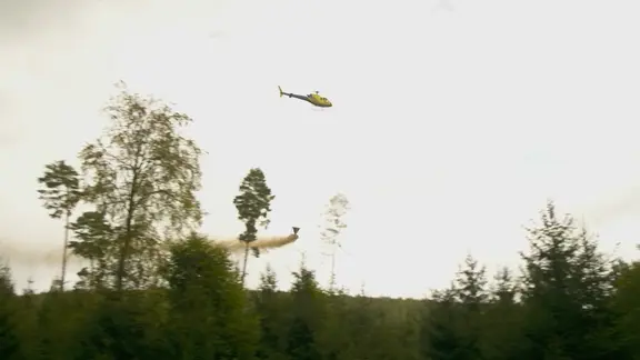 Ein Hubschrauber wirft Kalk ab