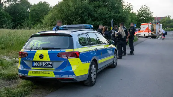 Polizisten und ein Rettungswagen auf einem Weg. 