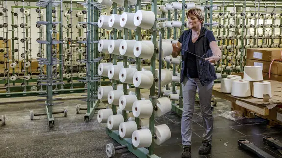 Eine Frau bei der Arbeit in einer Fabrikhalle.