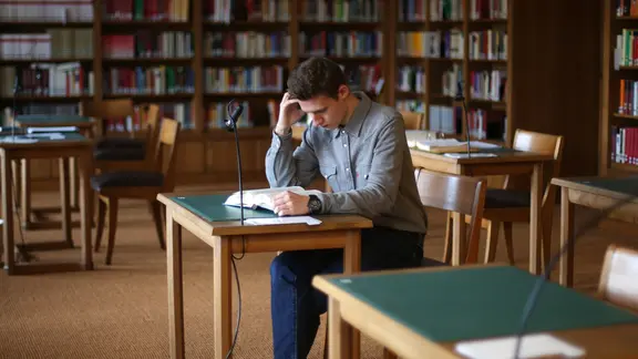 Ein Jurastudent sitzt in der Bibliothek beim Lernen.