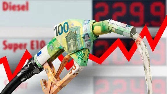 Zapfpistole aus gefalteten Euroscheinen vor Tankstellen-Preistafel und steigendem Graph Symbolbild zum Thema hohe Spritpreise