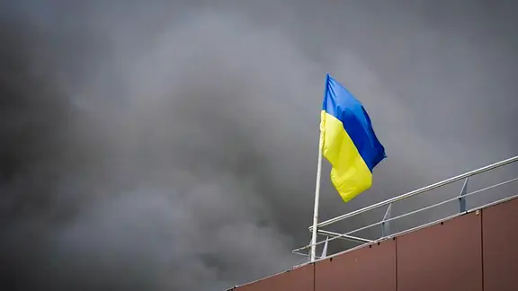 Eine ukrainische Flagge weht während eines Angriffs auf einem Gebäude.