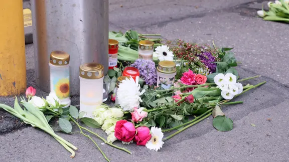 Blumen liegen an einem Poller.