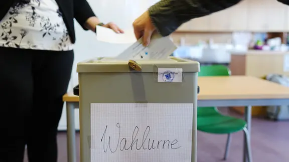 Ein Wähler wirft seinen gefalteten Stimmzettel in die Wahlurne in einem Wahllokal