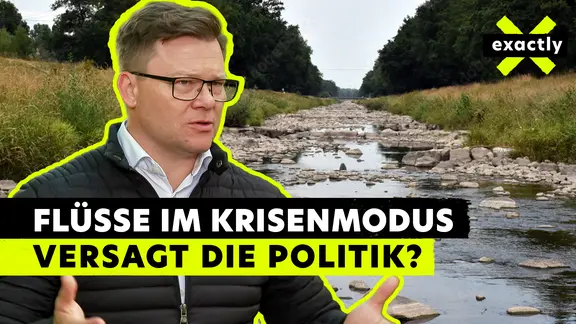 Bundesumweltminister Carsten Schneider vor einem Fluss mit Niedrigwasser