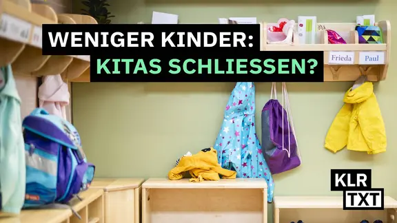 Bunte Kinderkleidung hängt an einer Garderobe.