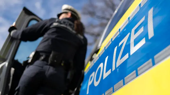 Eine Polizistin steht an einem Einsatzfahrzeug.