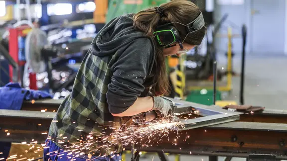 Eine Auszubildende zum Metallbauer arbeitet mit einem Schleifgerät.