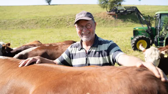 Axel Heinze steht auf einem Feld bei seinen Kühen. 
