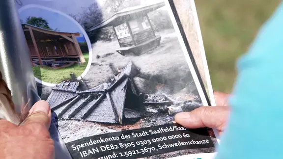 Ein Flyer mit einem Spendenaufruf zeigt das Bild einer abgebrannten Wanderhütte und die Bankverbindung eines Spendenkontos