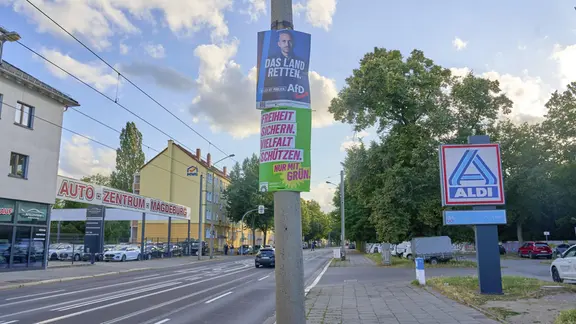 Zwei Wahlplakate hängen an einem Mast.