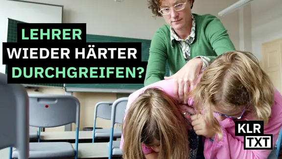 Eine Lehrerin packt Kinder, die sich im Klassenzimmer raufen, am Arm.