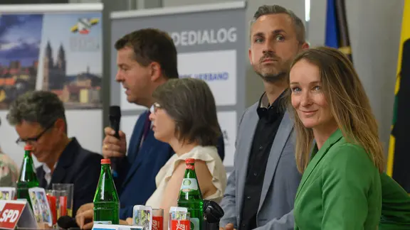 Fünf Personen stehen auf einer Bühne. Eine Frau (Claudia Wittig) und ein Mann (Ulrich Siegmund) schauen nach links.