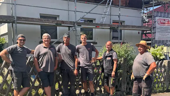Eine Gruppe von Handwerkern steht vor einer Baustelle