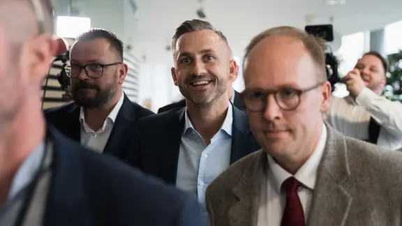 Drei Männer in Anzügen, zwei mit Brille, laufen in Richtung Kamera. In der Mitte ist Ulrich Siegmund von der AfD.