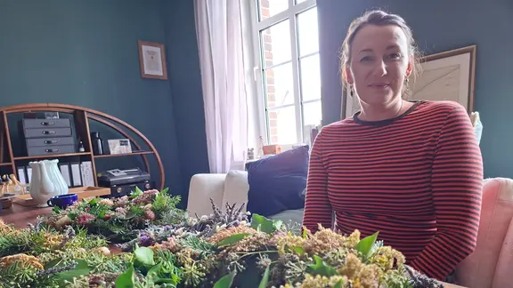 Aileen Maasdorff an einem Tisch vor Kräutern