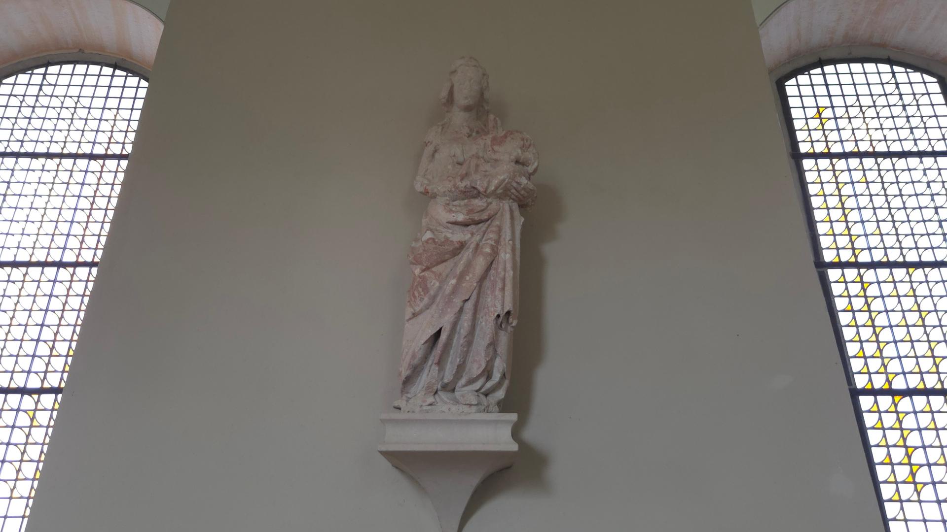 Eine Marien-Skulptur an einer Wand zwischen zwei hohen Rundbogenfenster.  | Anne Sailer