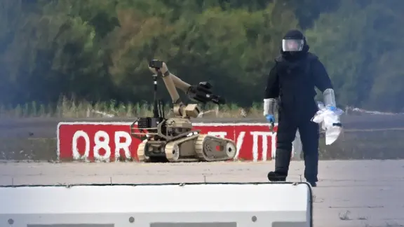 Ein Kriminaltechniker ist neben einem Sprengroboter in der Nähe eines ukrainischen Flugzeugs auf dem Flughafen Leipzig/Halle im Einsatz.