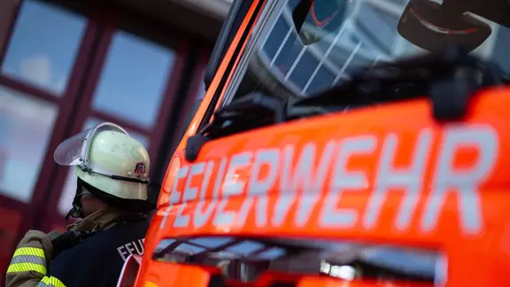 Ein Feuerwehrmann steht neben einem Einsatzfahrzeug der Feuerwehr