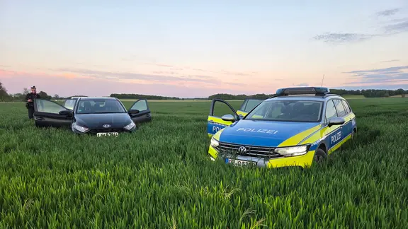 Ein Polizeiauto und ein PKW stehen in einem Getreidefeld