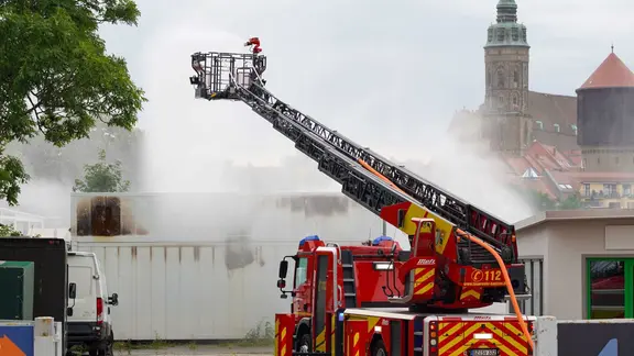 Die Feuerwehr löscht mit einer ferngesteuerten Spritze einen Brand in einem Batteriespeicher. Aus Sicherheitsgründen mussten mehrere Menschen ihre Wohnungen in direkter Nähe der Anlage verlassen.
