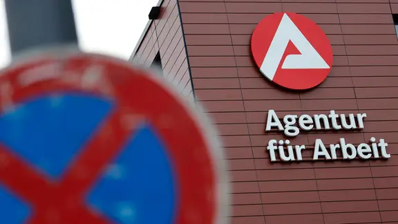 Logo an der Agentur für Arbeit. Im Vordergrund ein Halteverbotsschild