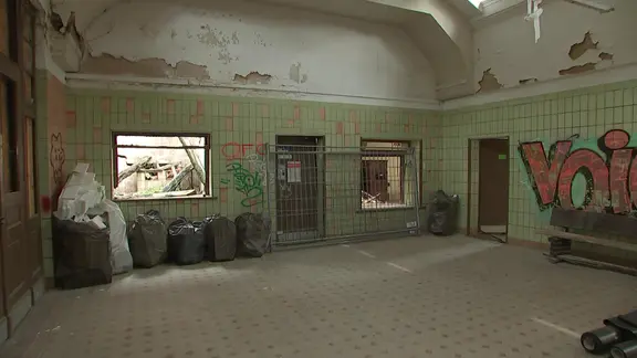 Bahnhofshalle mit bemalten Wänden und Bauzaun