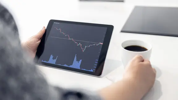 Eine Frau hält ein Tablet mit einem Börsenchart