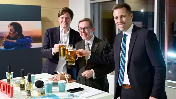 Drei Männer an einem Stehtisch