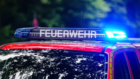 Symbolfoto: Aufschrift Feuerwehr auf Feuerwehrauto, mit Blaulicht