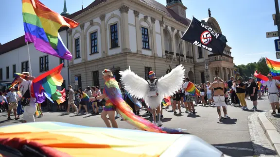 Ein Teilnehmer des Christopher-Street-Day mit riesigen Engelsflügeln steht vor dem Magdeburger Rathaus und schwenkt eine Fahne mit der Schrift «Gegen Nazis». 