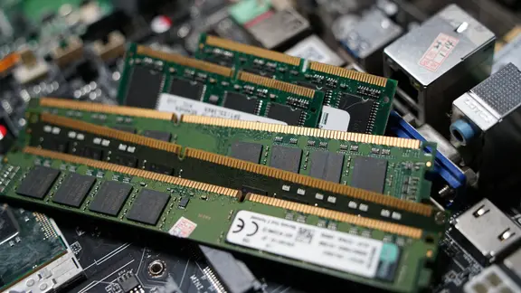 Mehrere grüne Arbeitsspeicher-Module (RAM) liegen auf einer geöffneten Computer-Hauptplatine.