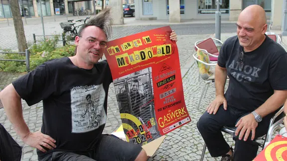 Ein Mann hält ein Plakat nach oben, ein anderer schaut es an