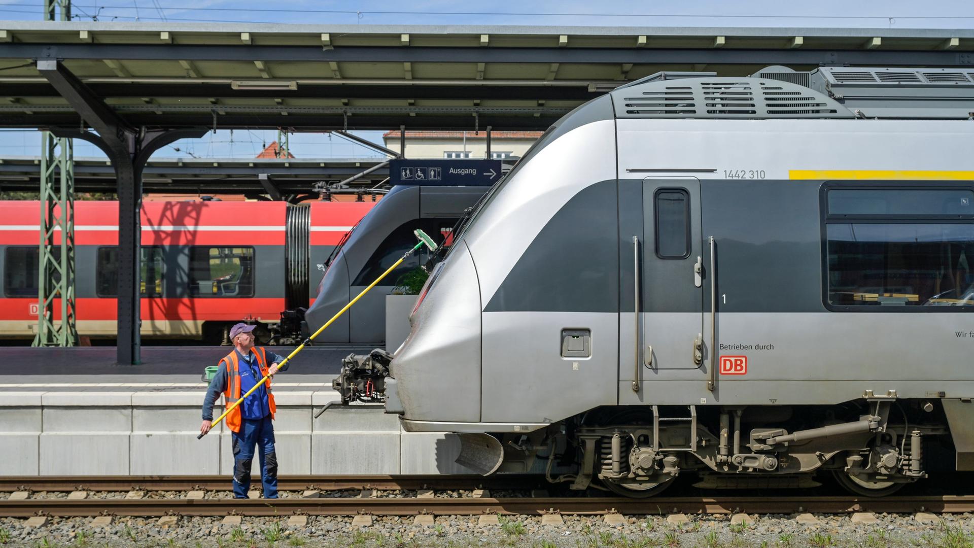 Ein Mann reinigt die Frontscheibe eines Zugs in einem Bahnhof. | IMAGO / Joko
