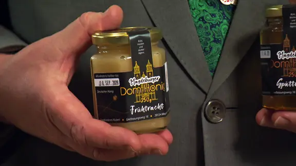 Ein Mann hält ein Glas Honig