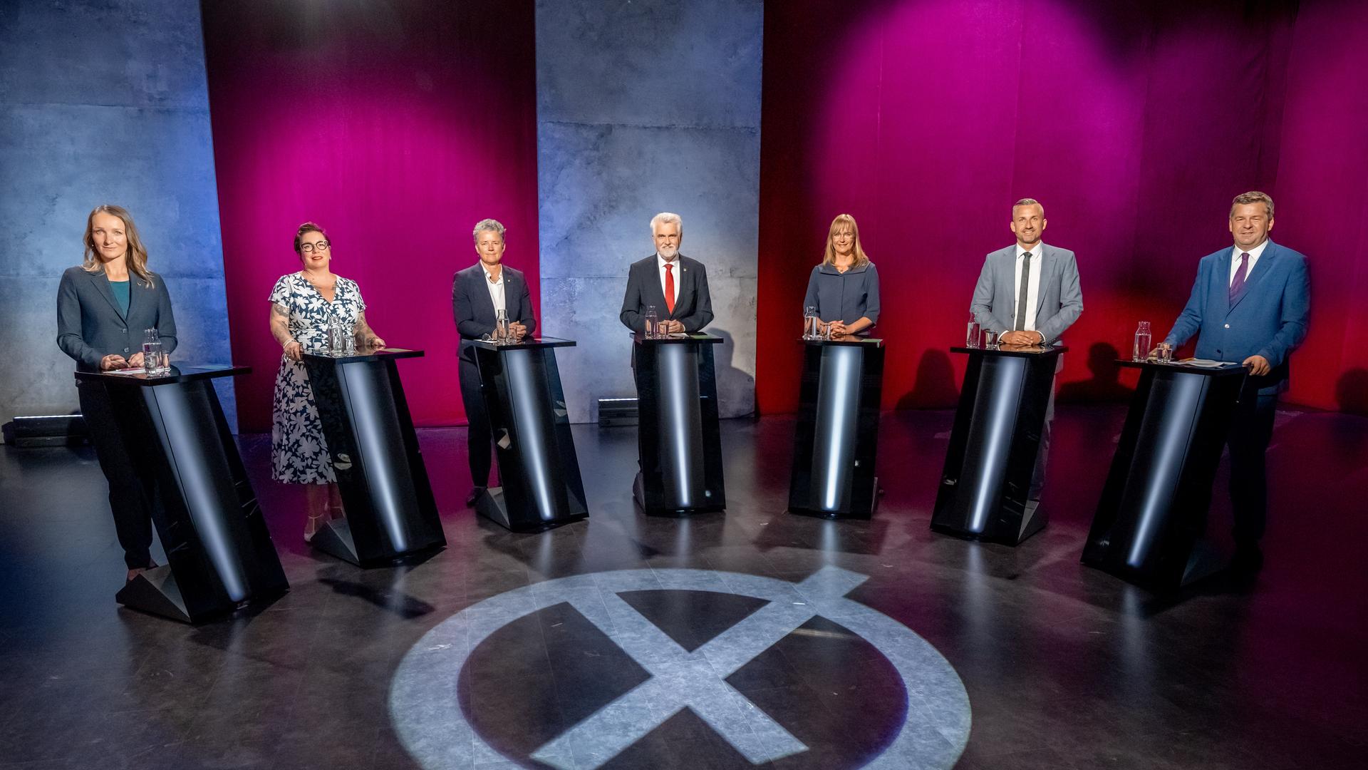 Sieben Menschen stehen in einem Halbkreis zusammen. Jeder hinter einem Pult.  | Andreas Lander
