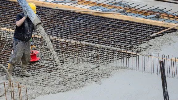 Bauarbeiter gießt Beton für eine Bodenplatte